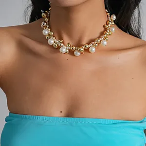 Primo piano di una collana girocollo con perle e grani dorati sul collo della modella.