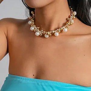 Vista dettagliata di una collana con grosse perle dorate e bianche sul collo modella