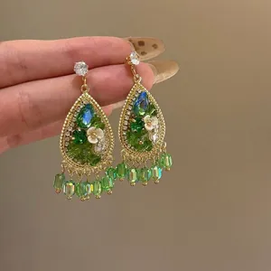 Détail rapproché de boucles d'oreilles style forêt avec zircon vert et motifs floraux