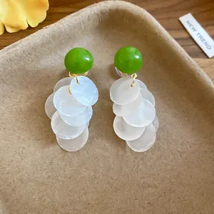 Détail des boucles d'oreilles Monet Garden avec perles vertes et disques de nacre blancs