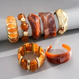 Detailopname van geometrische acryl gemarmerde armbanden en retro gouden armbanden