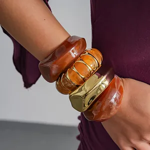 Close-up detail van onregelmatige geometrische acryl armbanden met amberkleurige marmering