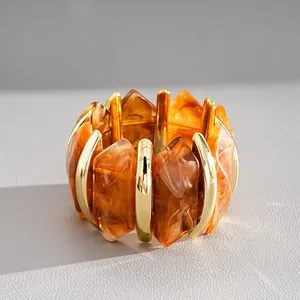 Detail van retro geometrische acryl armband met amber marmerpatroon en goud metaal.
