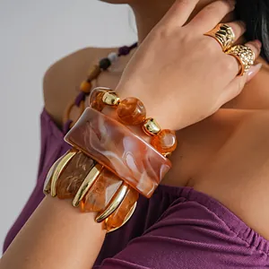 Detailweergave van onregelmatige geometrische gemarmerde acryl armbanden met gouden accenten