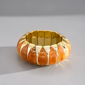 Detailopname van een vintage armband van oranje gemarmerd acryl en goud metaal