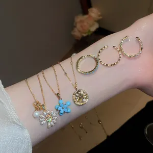 Dettaglio di collane e anelli placcati oro 18k con eleganti ciondoli a fiore in zircone