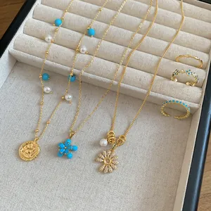 Dettaglio di collane e anelli placcati oro 18 carati con ciondoli a fiore di zircone in vassoio.