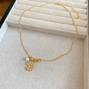 Dettaglio di una collana placcata oro 18k con fiore in zircone e pendente di perla