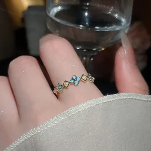 Primo piano di un anello a fiore dorato con smalto blu e perle al dito