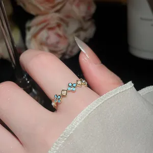 Vista macro dettagliata di un anello a fiori azzurri placcato oro 18k con eleganti perle