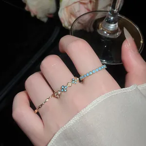 Primo piano di un elegante set di anelli d'oro a fiori con pietre blu turchese sul dito
