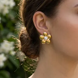 Vue détaillée d'une boucle d'oreille fleur dorée 18K avec une perle sur un mannequin