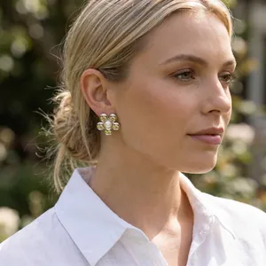 Gros plan de boucles d'oreilles fleurs dorées avec centre en perle sur un mannequin