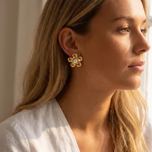 Gros plan d'un mannequin portant des boucles d'oreilles fleur dorée avec perle