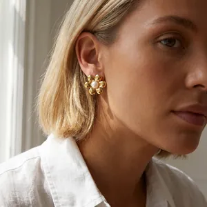 Un gros plan de boucles d'oreilles fleur plaquées or 18 carats avec perle centrale