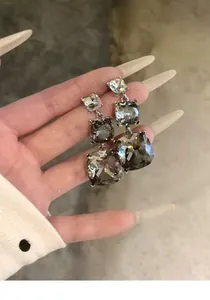 Dettaglio degli eleganti orecchini pendenti in cristallo grigio fumo quadrato con ago