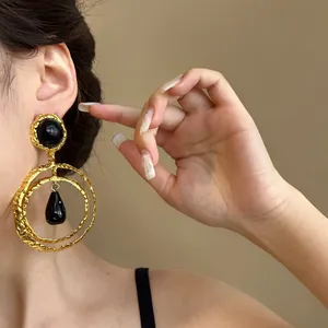 Close-up view of vintage oversized gold-textured earrings with black resin teardrop details