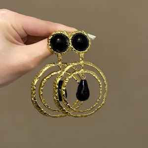 Macro detail showing the hammered gold texture of these vintage black resin drop earrings.