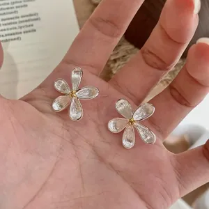 Elegante zilveren traanvormige bloem oorbellen met goud centrum getoond op de hand