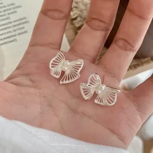 Elegante zilveren vlinder oorknopjes met parels gepresenteerd op een natuurlijke hand