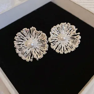 Detailweergave van elegante zilveren bloem oorbellen met een glanzende centrale parel