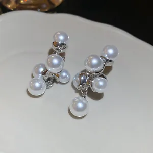 Detailopname van de elegante witte parelcluster en zilveren druppeloorbellen details