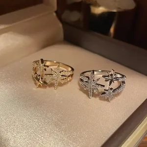 Primo piano di eleganti anelli aperti a stella con zirconi in oro e argento di lusso