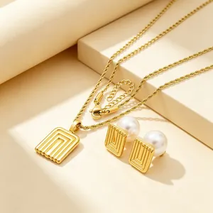 Close-up of vintage gold-plated geometric necklace and pearl earrings jewelry set