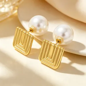 Macro view of French retro earrings with golden geometric square and large white pearl