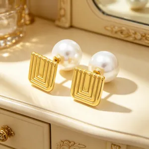 Close-up of French vintage gold geometric earrings with large glossy pearls