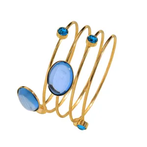Close-up of a French style spiral gold cuff bracelet featuring vibrant blue gemstones