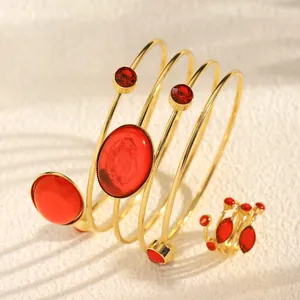 Close-up of a gold-tone spiral bangle and matching ring set with red gemstones