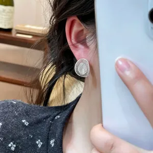 Close-up shot of a minimalist silver hollow mesh oval stud earring being worn gracefully