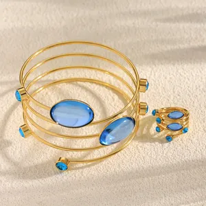 Detailed view of French-style golden spiral bracelet and ring set with blue gems