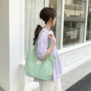 Asian model carrying a green polka dot canvas tote bag in a minimalist street setting