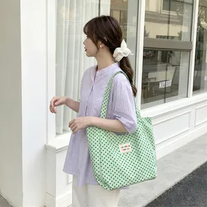 Large capacity green polka dot canvas tote bag for women in a street style setting