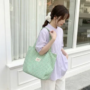 Mint green canvas tote bag with brown polka dot pattern and logo tag detail for women