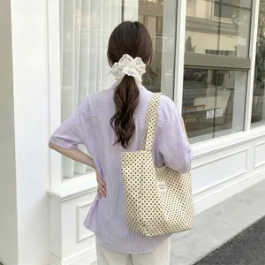 Female model wearing a large capacity cream polka dot canvas tote bag for daily commuting