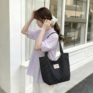Black polka dot canvas tote bag carried by a model, showing large capacity and style.