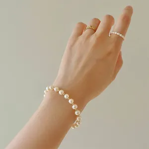 Close-up of elegant pearl bracelet with gold beads worn on a model's wrist and fingers