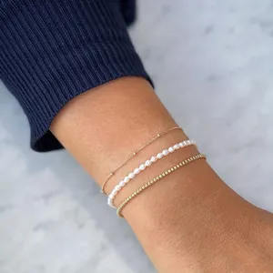 Elegant stacked natural freshwater pearl and gold beaded bracelets on female wrist