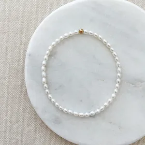 Macro detail of a baroque freshwater pearl bracelet with a single gold accent bead.