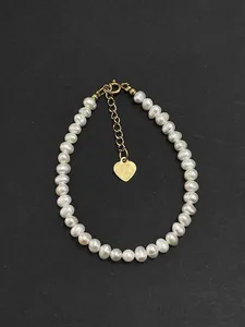 Close-up view of a natural freshwater pearl bracelet featuring a gold heart charm detail