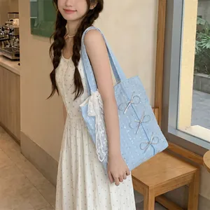 Detailed side view of light blue canvas shoulder bag with silver sequins and bows