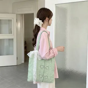 Side view of a mint green canvas tote bag with lace and bow details worn by a young model