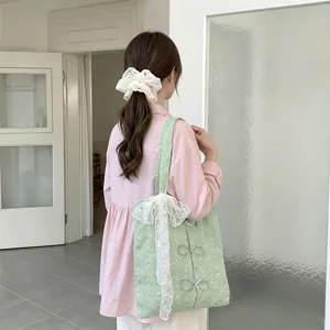 Lifestyle detail of a light green canvas tote with sequin bows and lace ribbon.