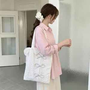 Detailed view of a white sequined canvas tote bag with bows carried by a model.