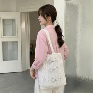 Close-up detail of a stylish white sequin tote bag with ribbon bows on a model shoulder