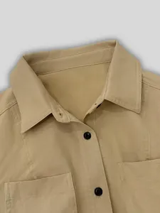 Close-up of khaki lapel shirt dress featuring black buttons and chest pockets details