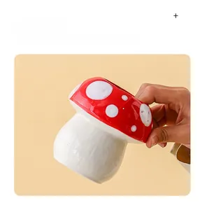 Gros plan d'une main tenant un joli pot à crayons en céramique en forme de champignon
